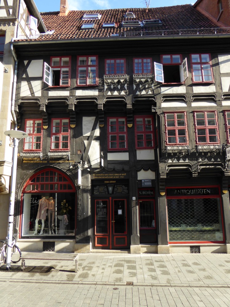 Fachwerkhaus mit Erdgeschoss, Zwischengeschoss und Oberstockwerk. Links tritt das Zwischengeschoss als Erker hervor, rechts ist die Vorkragung erst unter dem Obergeschoss. Ganz rechts hat das Haus eine ehemalige Toreinfahrt mit Spitzbogen, die zum Schaufenster ausgebaut ist. Darin stehen zwei Schaufensterpuppen. Die heutige Tür ist in der Mitte. Rechts ist ein eckiges Schaufenster, darüber die Beschriftung: Antiquitäten. Über der ehemaligen Einfahrt und der heutigen Tür sind Inschriften in goldfarbenen Lettern angebracht. An den Vorkragungen gibt es geschnitzte Verzierungen, die aber nicht figürlich sind. Auffällig sind unter den Fenstern im Erker und unter einem Fensterpaar im Oberstockwerk kreuzweise schräge Hölzer, die fast die gesamten Gefache ausfüllen. Das Holz ist dunkelbraun, die Gefache weiß.